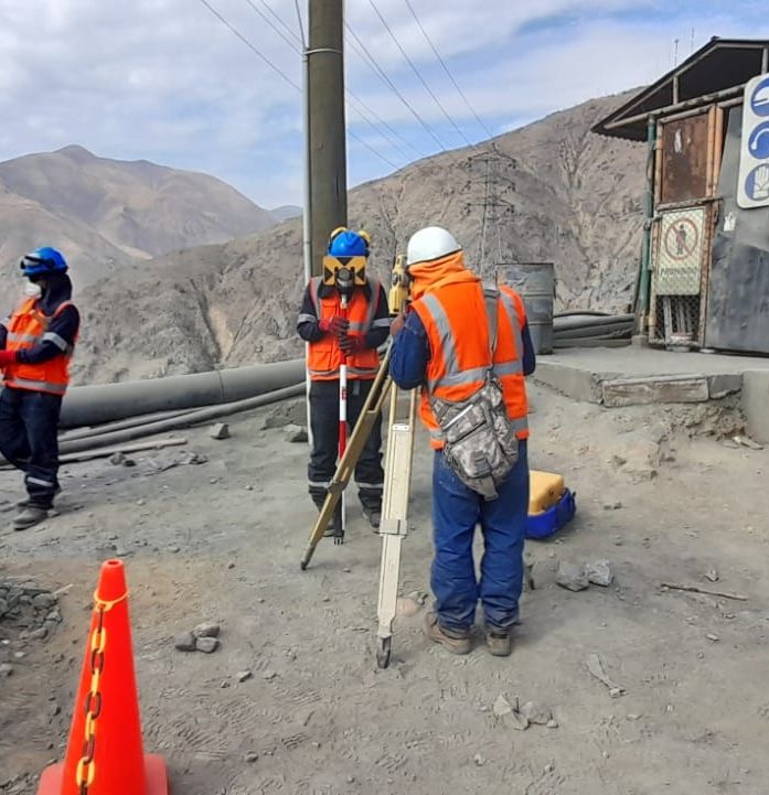 Topógrafos con estación total y prisma trabajando en campo